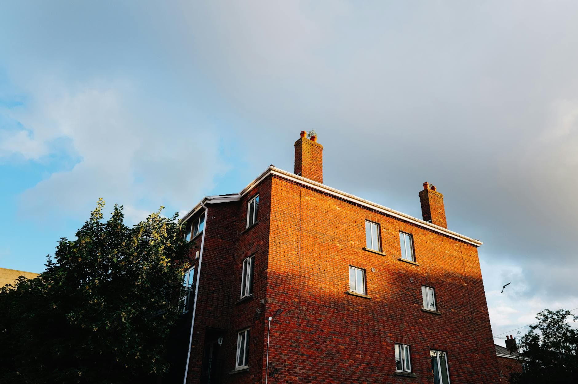 Brick chimney on residential rooftop against blue sky