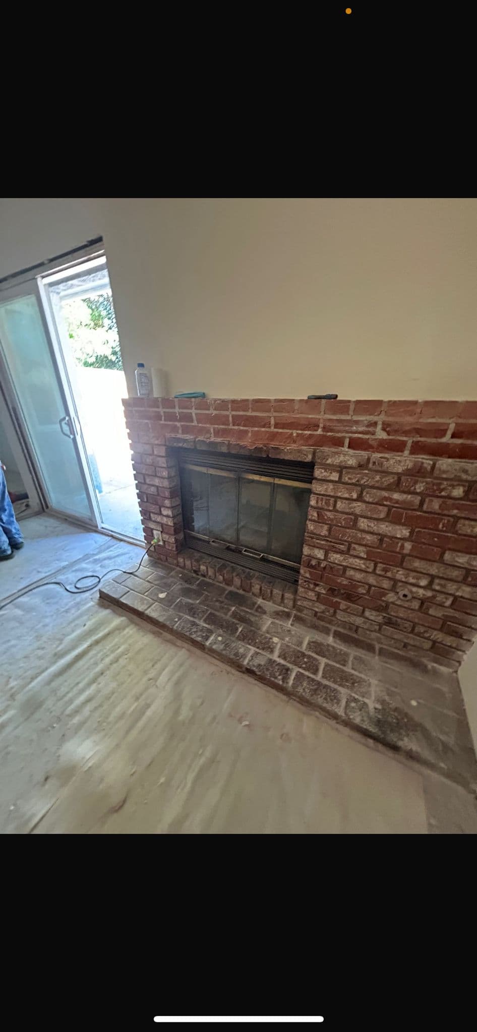 Original brick fireplace with glass doors before remodel showing dated surround