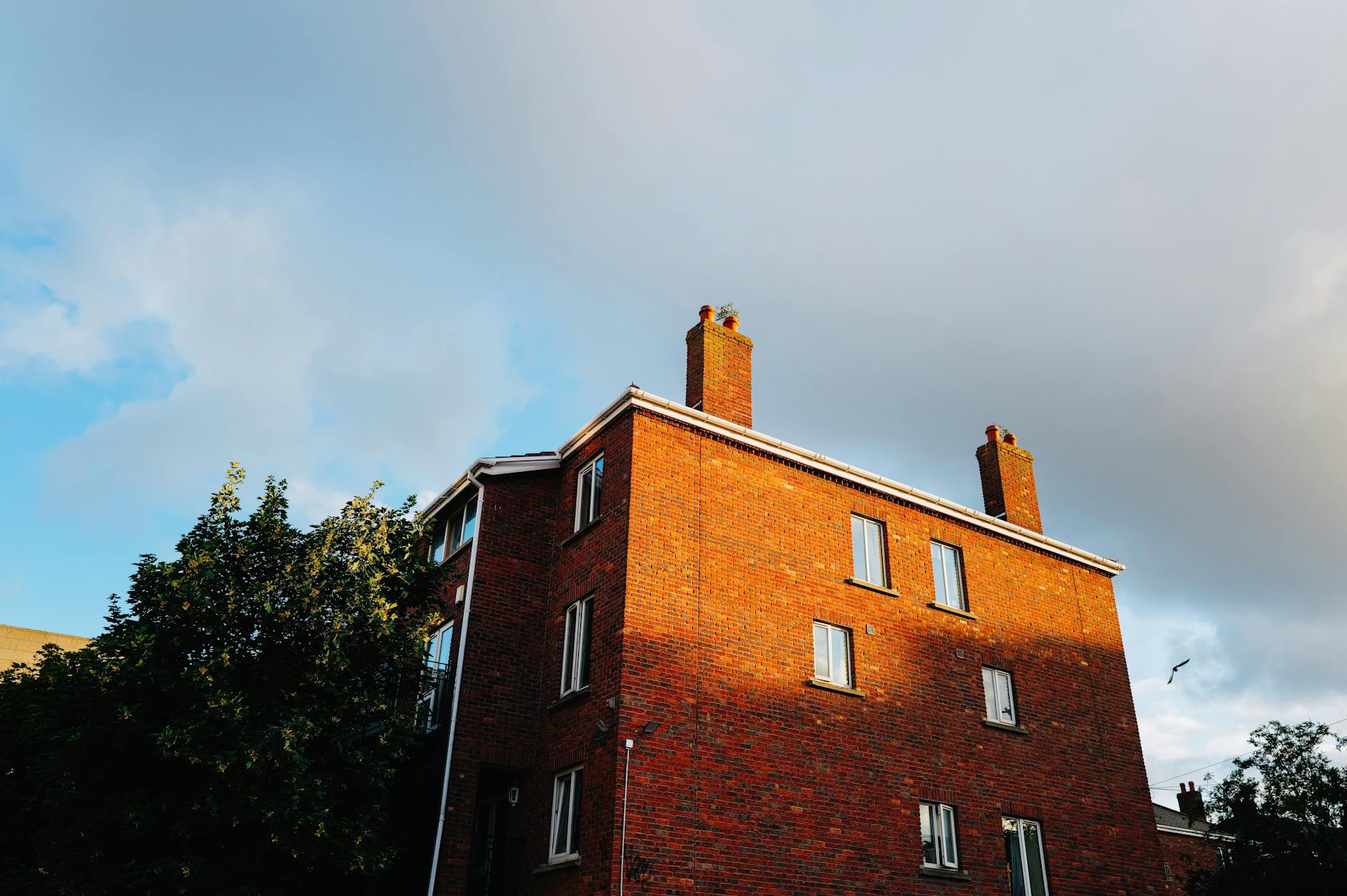 Brick chimney on residential rooftop against blue sky